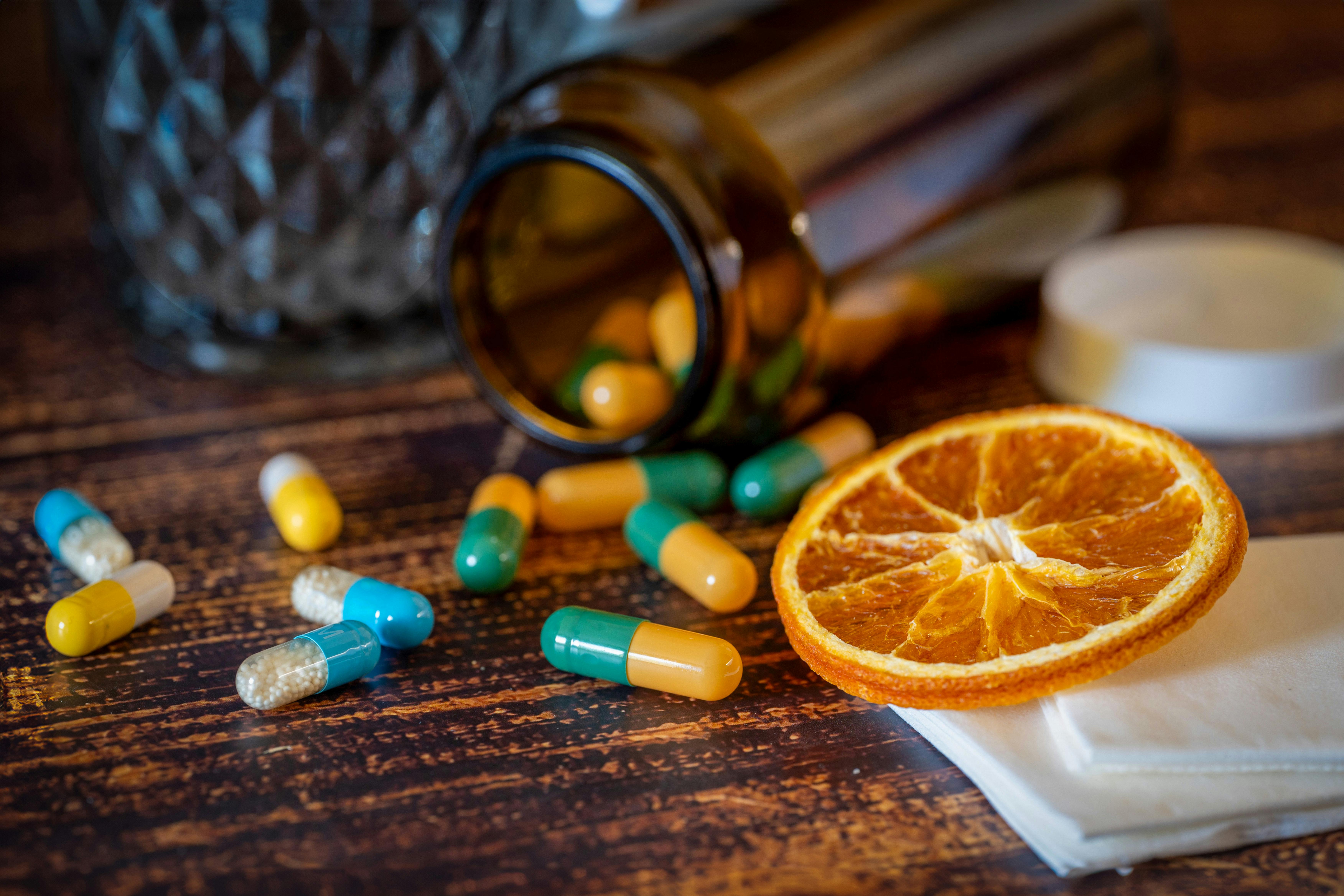 Pills in a bottle and a slice of orange