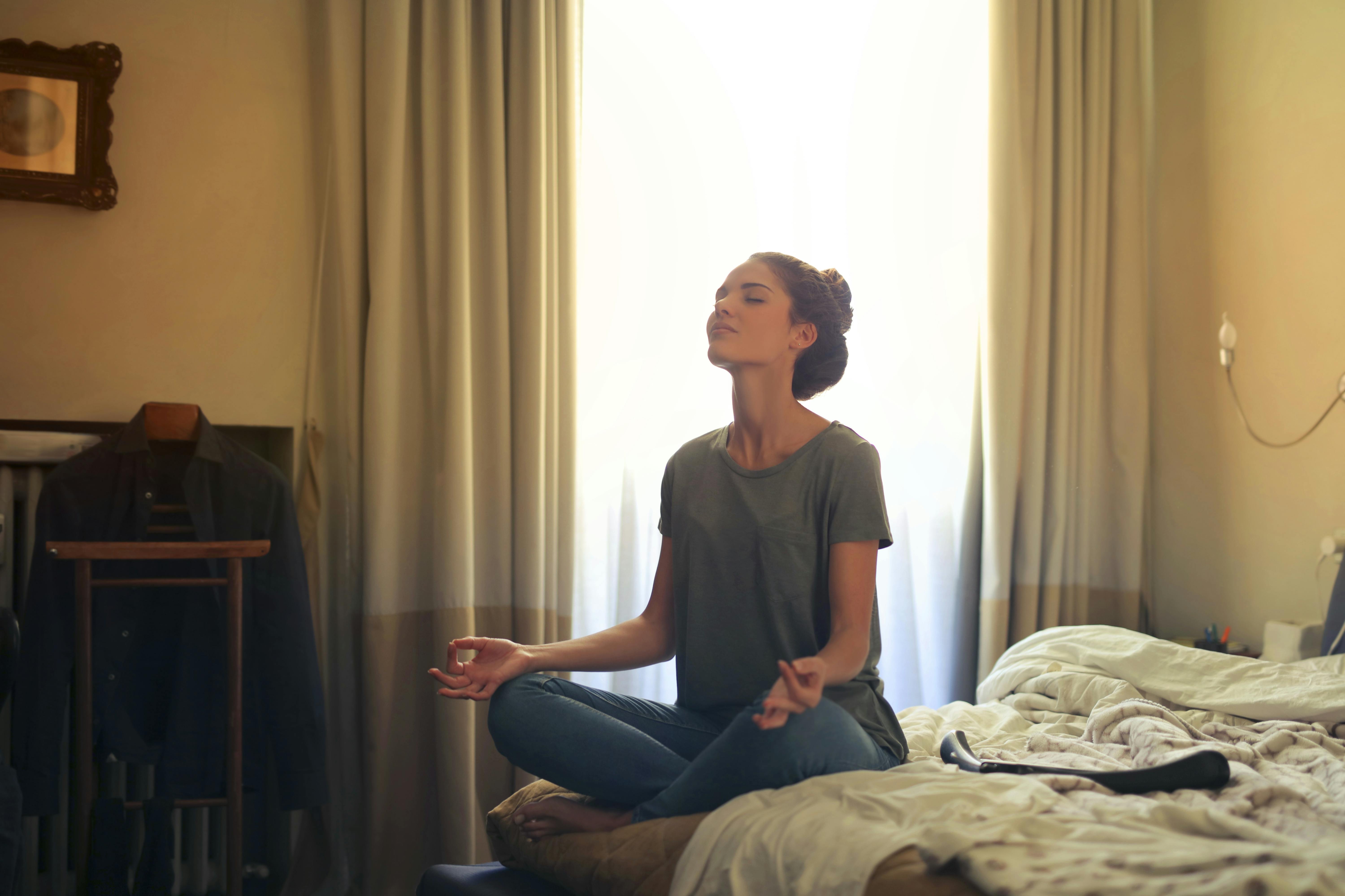A woman sitting cross-legged on a bed, meditating
