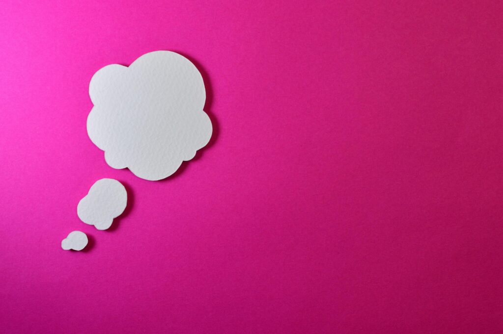 A white thought bubble on a bright pink packground