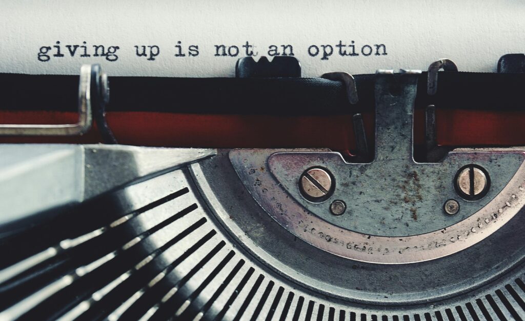 Paper in a typewriter. The words "giving up is not an option" have been typed on it