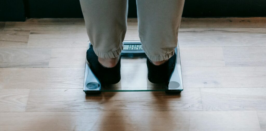 Someone in socks and joggers stood on scales