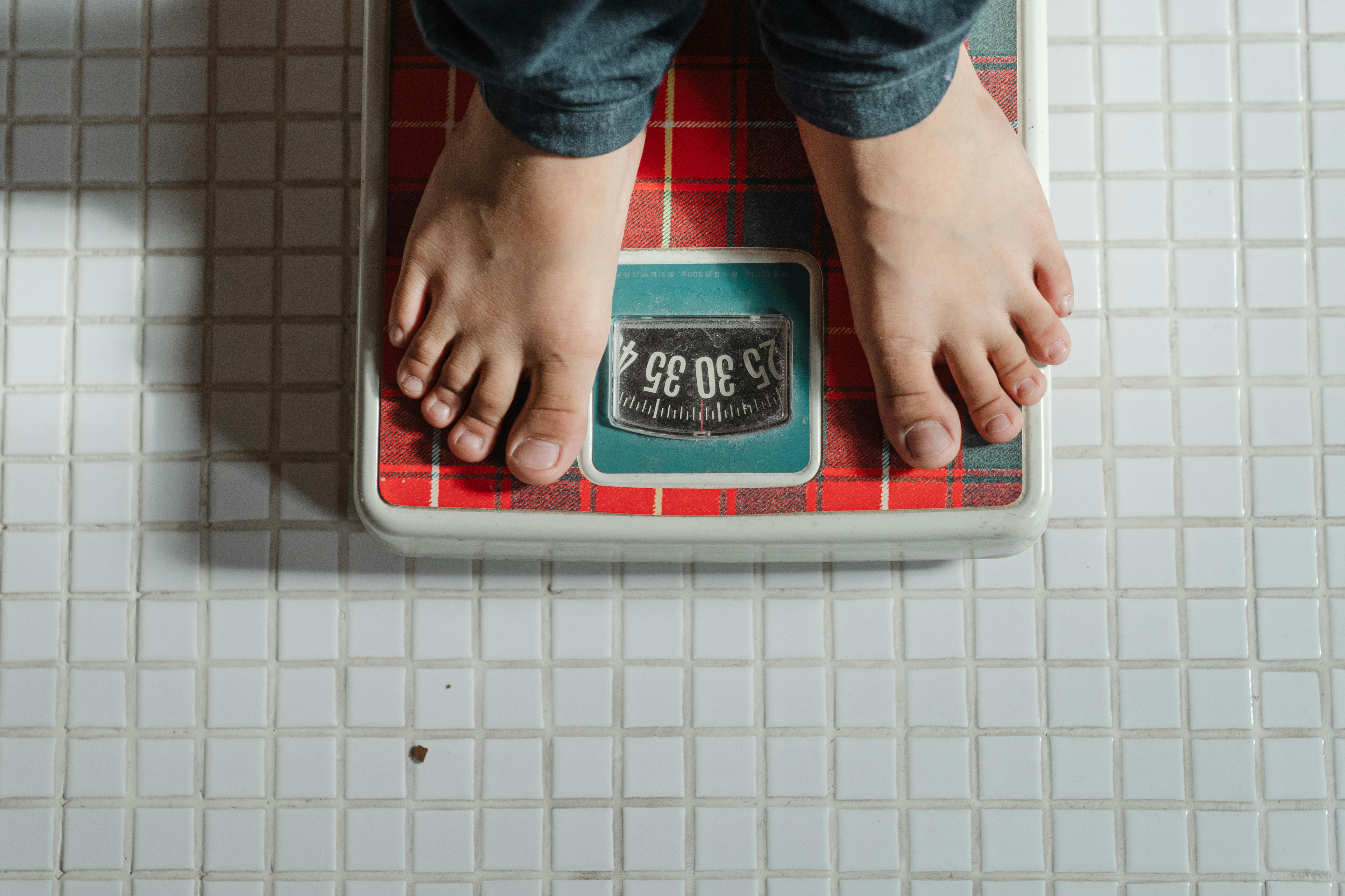 A person wearing jeans stands on a bathroom scale