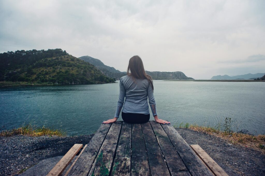 A woman sitting on a picnic bench overlooking a lake