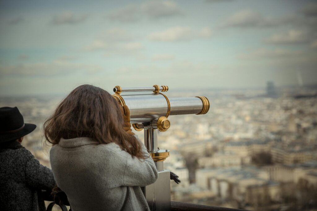 A woman looking at a city through a telescope