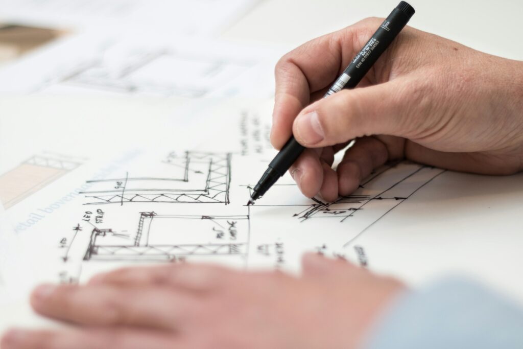 A person holding a pen and drawing out plans